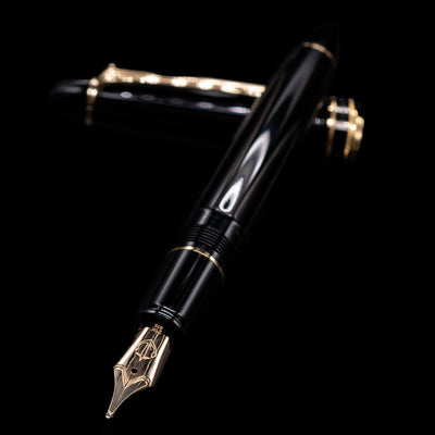 Sailor 1911L Fountain Pen - Black / King Eagle Nib laying across its own cap, crossed, with a focus on the nib.