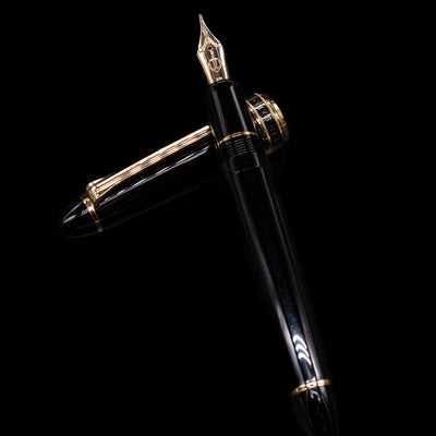 Sailor 1911L Fountain Pen - Black / King Eagle Nib laying on top of its cap in a crossed position showing full view of the entire uncapped pen.