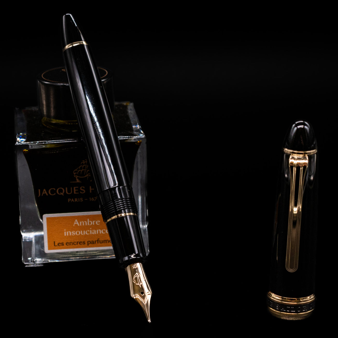 Sailor 1911L Fountain Pen - Black / King Eagle Nib leaning on an ink bottle uncapped showcasing the detailing on the nib.