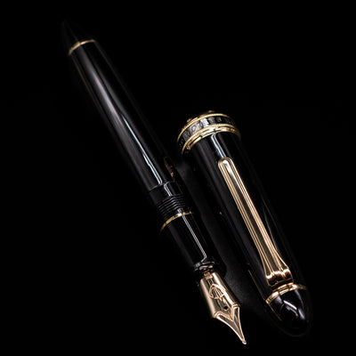 A full view of the Sailor 1911L Fountain Pen - Black / King Eagle Nib uncapped, with its cap laying next to the pen. 