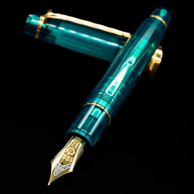 Sailor Professional Gear King of Pens Teal Green Wancher Fountain Pen - Preowned laying across its own cap, crossed, with a focus on the nib.