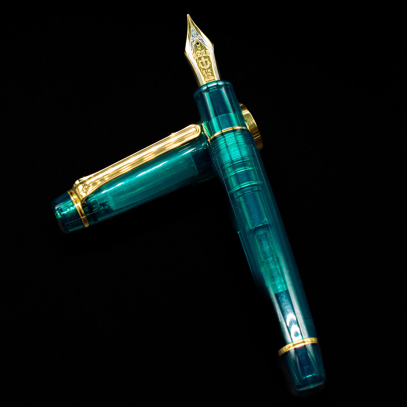 Sailor Professional Gear King of Pens Teal Green Wancher Fountain Pen - Preowned laying on top of its cap in a crossed position showing full view of the entire uncapped pen.