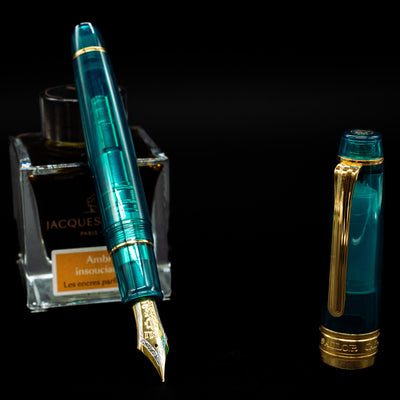 Sailor Professional Gear King of Pens Teal Green Wancher Fountain Pen - Preowned leaning on an ink bottle uncapped showcasing the detailing on the nib.
