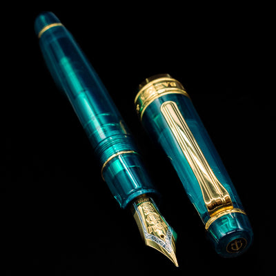  A full view of the Sailor Professional Gear King of Pens Teal Green Wancher Fountain Pen - Preowned uncapped, with its cap laying next to the pen. 