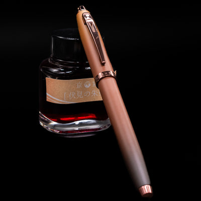 Sheaffer 100 Fountain Pen - Coffee (Special Edition) capped, leaning against an ink bottle. 