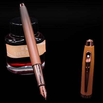 Sheaffer 100 Fountain Pen - Coffee (Special Edition) leaning on an ink bottle uncapped showcasing the detailing on the nib.