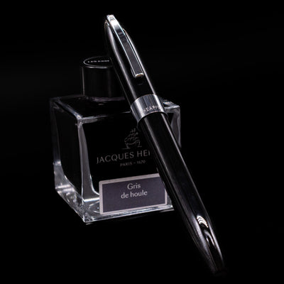 Sheaffer Legacy Fountain Pen - Black capped, leaning against an ink bottle. 