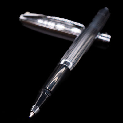 Sheaffer Sagaris Rollerball Pen - Chrome laying across its own cap, crossed, with a focus on the tip.