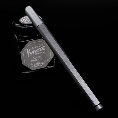 Stilform ARC Gel Pen – Comet Grey Aluminum capped, leaning against an ink bottle. 