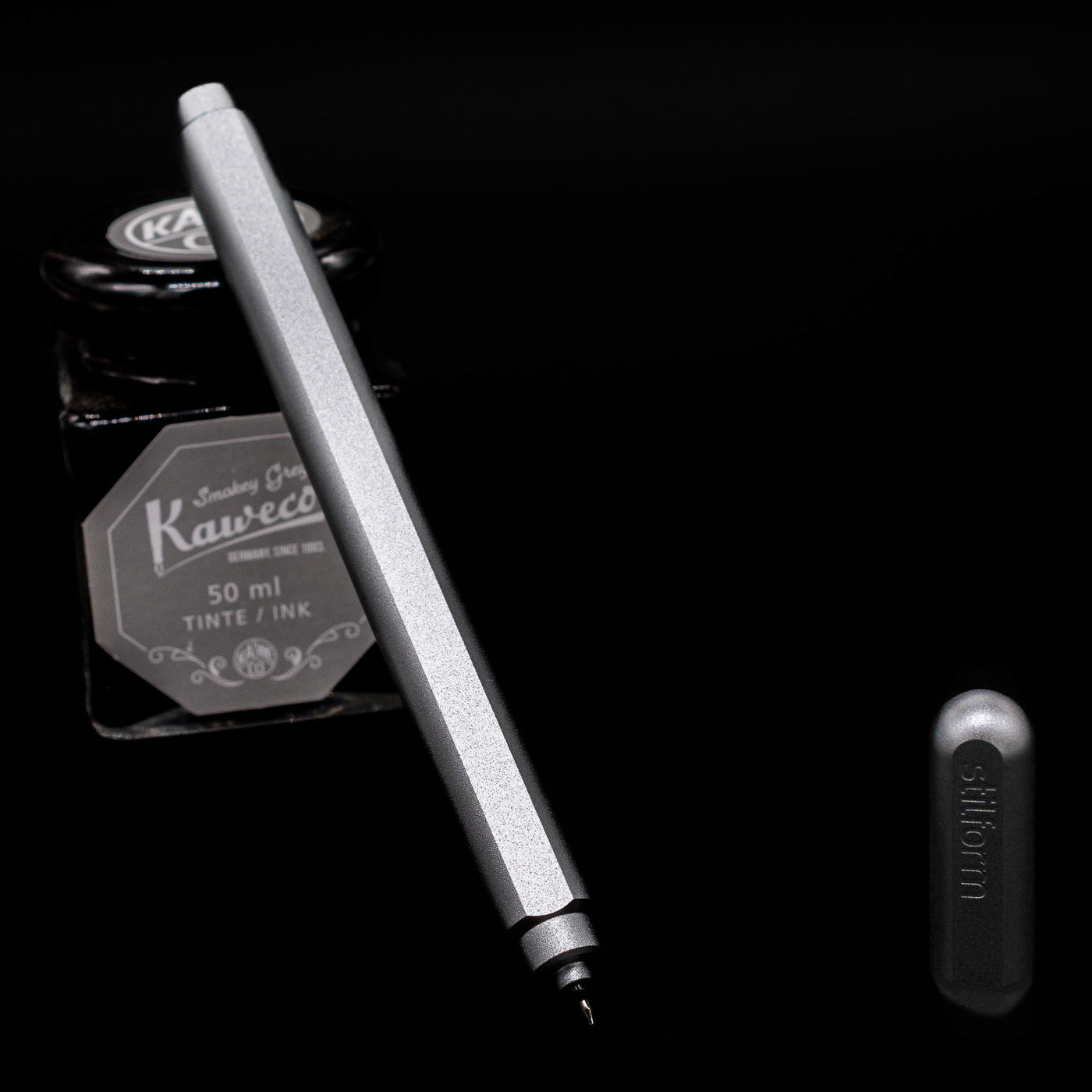 Stilform ARC Gel Pen – Comet Grey Aluminum leaning on an ink bottle uncapped showcasing the detailing on the nib.
