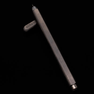 Stilform ARC Gel Pen – Titanium DLC laying on top of its cap in a crossed position showing full view of the entire uncapped pen.