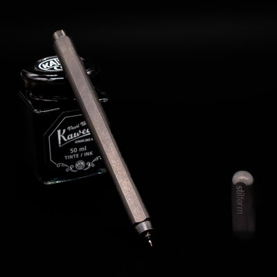 Stilform ARC Gel Pen – Titanium DLC leaning on an ink bottle uncapped showcasing the tip.