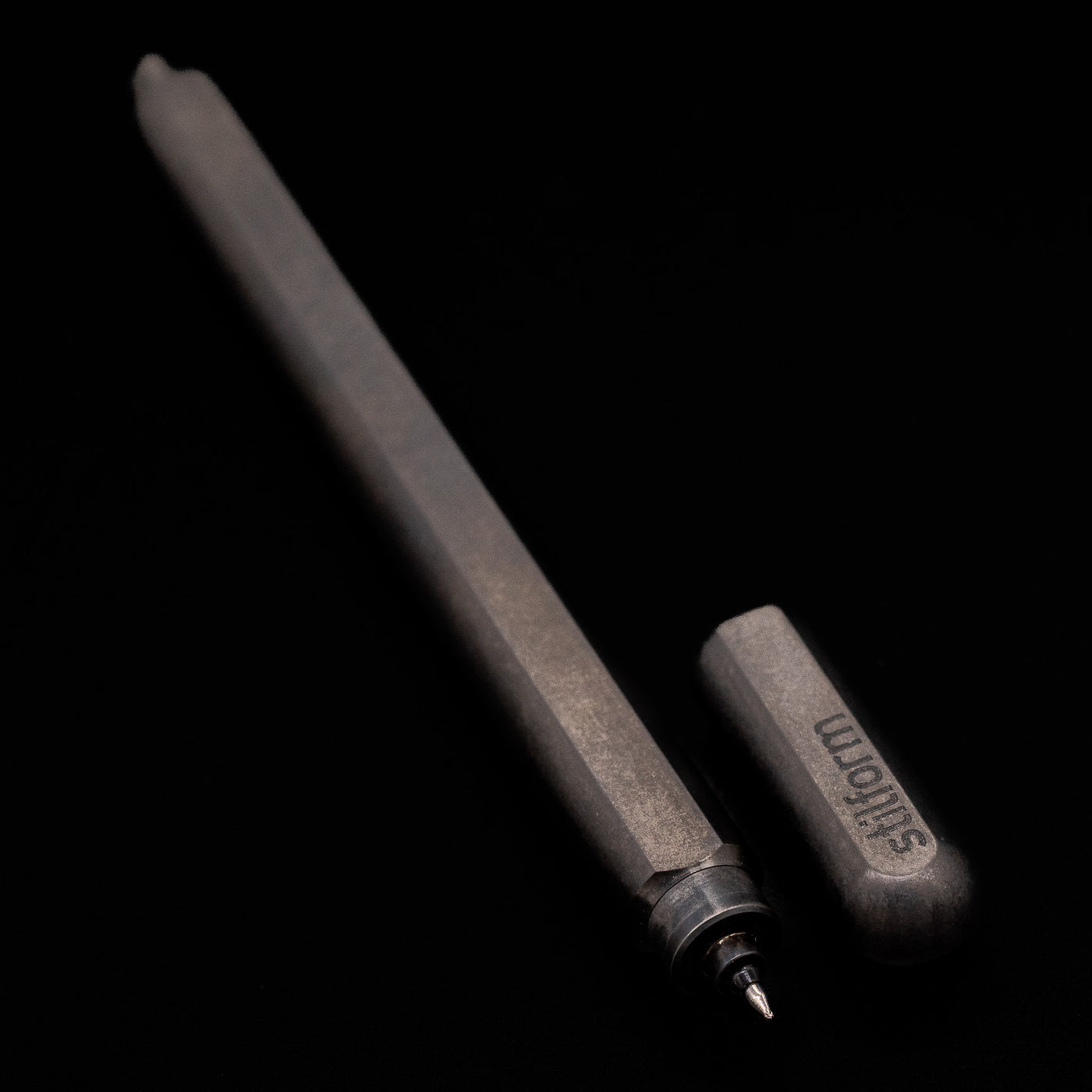  A full view of the Stilform ARC Gel Pen – Titanium DLC uncapped, with its cap laying next to the pen. 