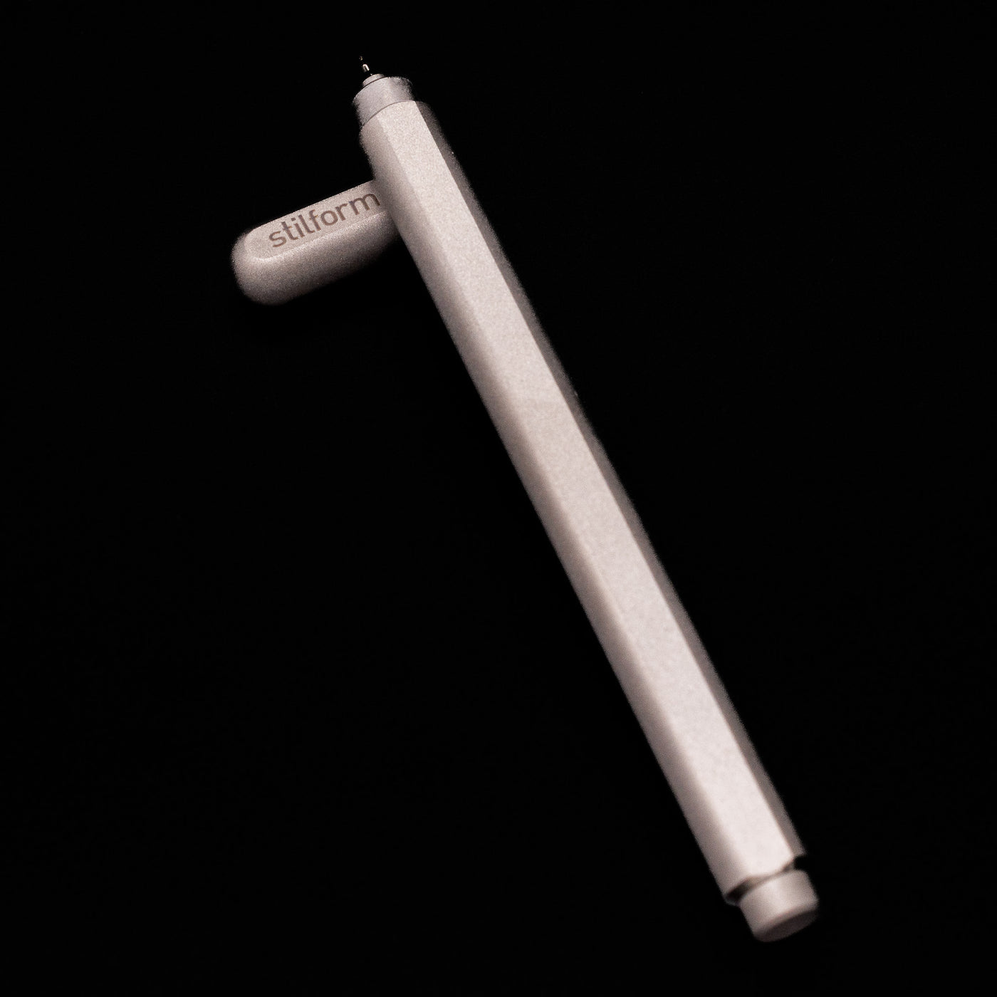Stilform ARC Gel Pen – Titanium Matte laying on top of its cap in a crossed position showing full view of the entire uncapped pen.