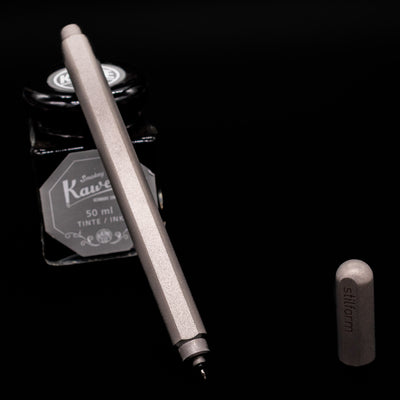 Stilform ARC Gel Pen – Titanium Matte leaning on an ink bottle uncapped showcasing the tip.