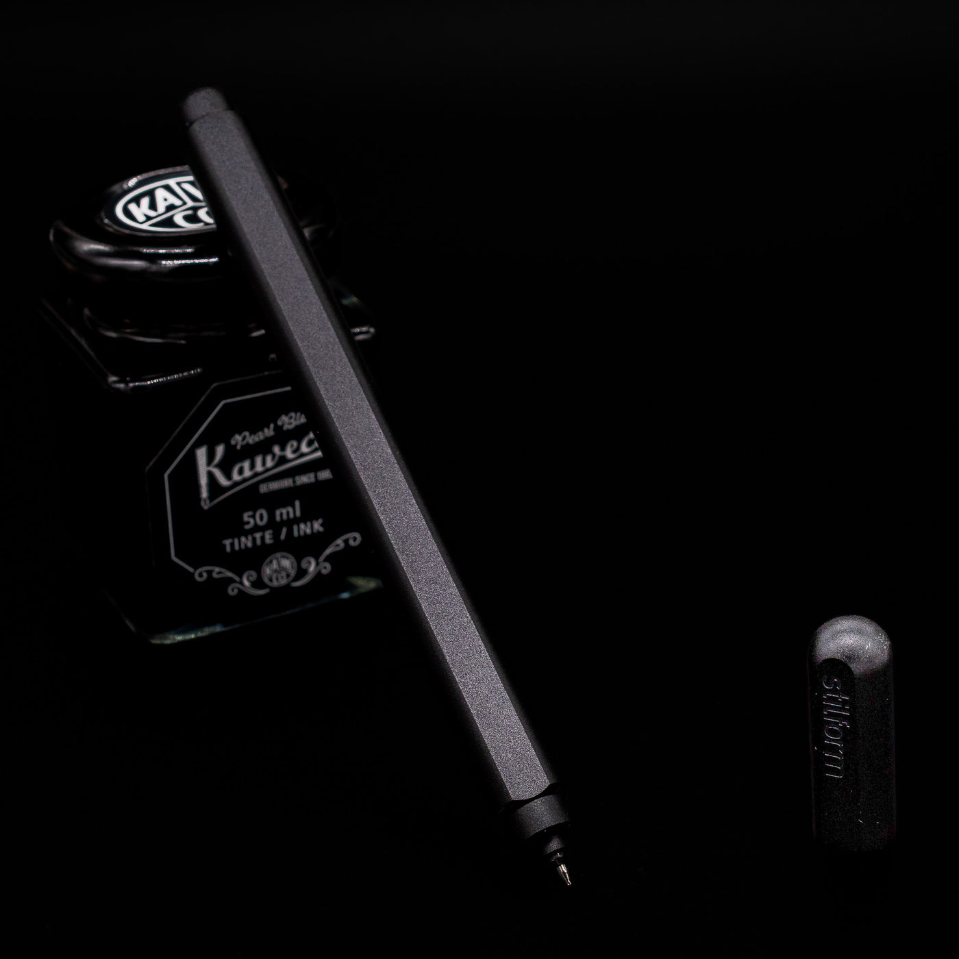 Stilform ARC Gel Pen – Warp Black Aluminum leaning on an ink bottle uncapped showcasing the tip.