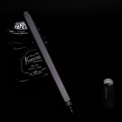 Stilform ARC Gel Pen – Warp Black Aluminum leaning on an ink bottle uncapped showcasing the tip.