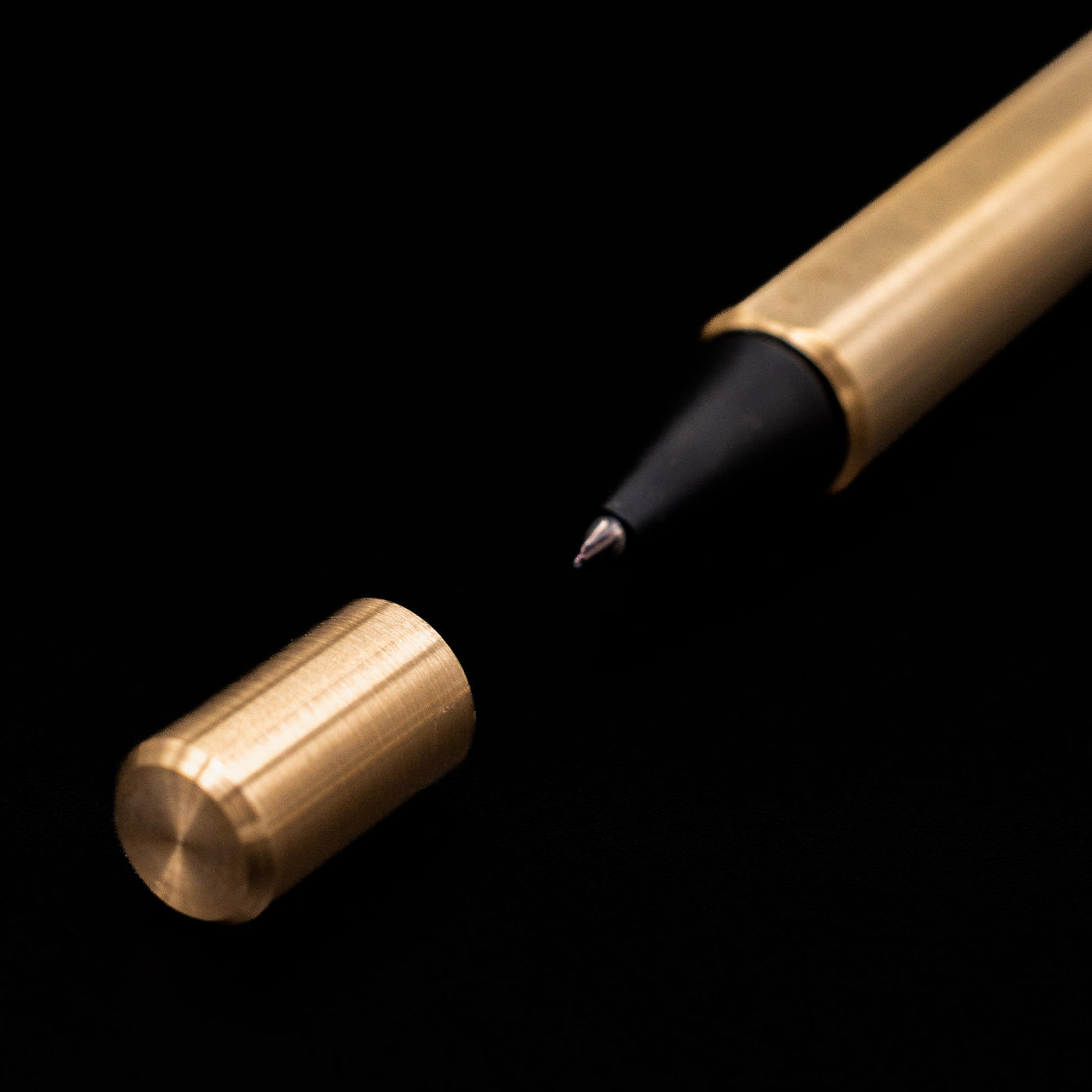 A macro shot of the Stilform FLOW Rollerball Pen – Brass Radial Brushed's tip and its small cap.