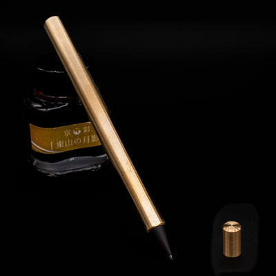 Stilform FLOW Rollerball Pen – Brass Radial Brushed leaning on an ink bottle uncapped showcasing the detailing on the tip.