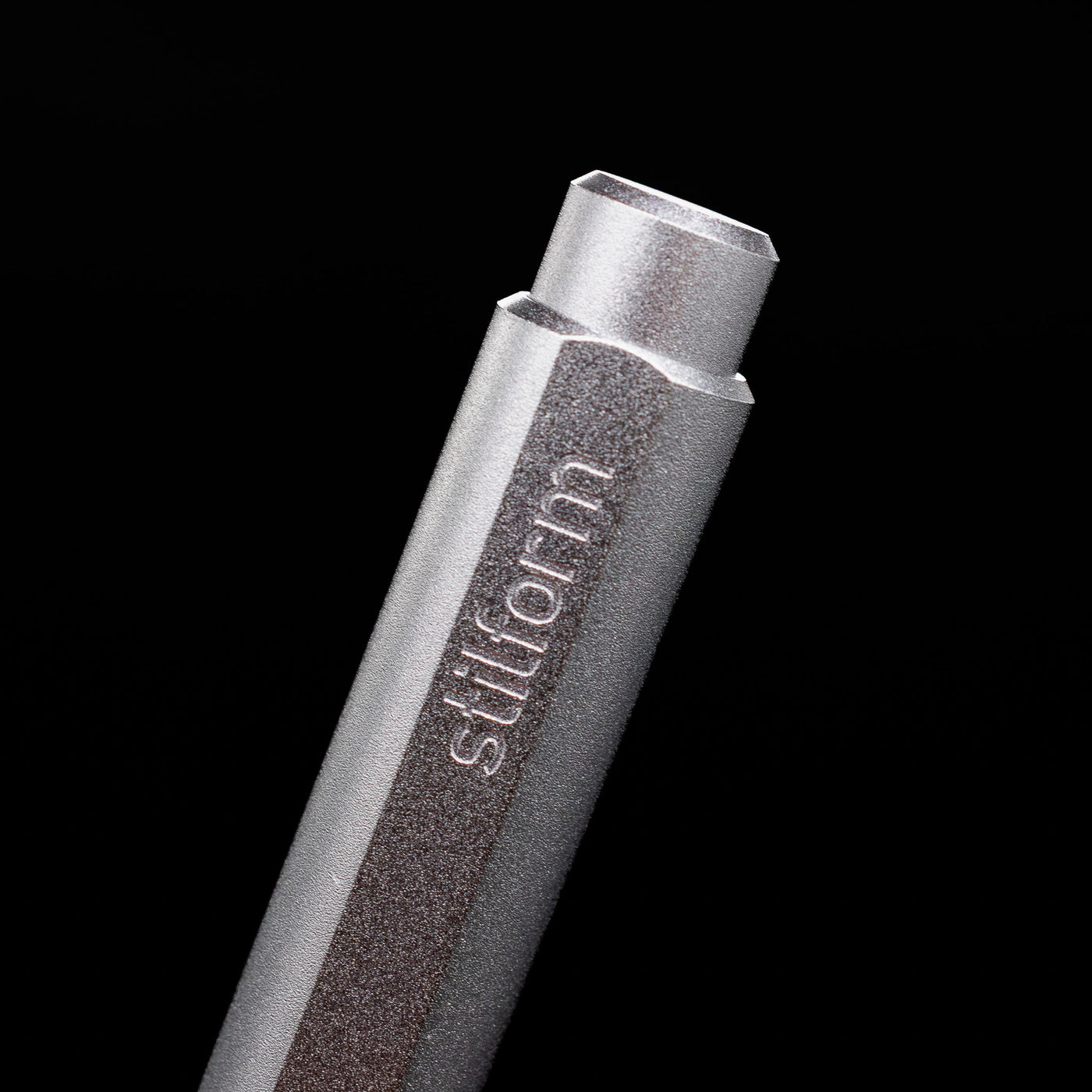 A macro shot of the logo on the cap of the Stilform FLOW Rollerball Pen – Comet Grey Aluminum.