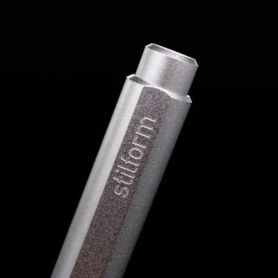 A macro shot of the logo on the cap of the Stilform FLOW Rollerball Pen – Comet Grey Aluminum.