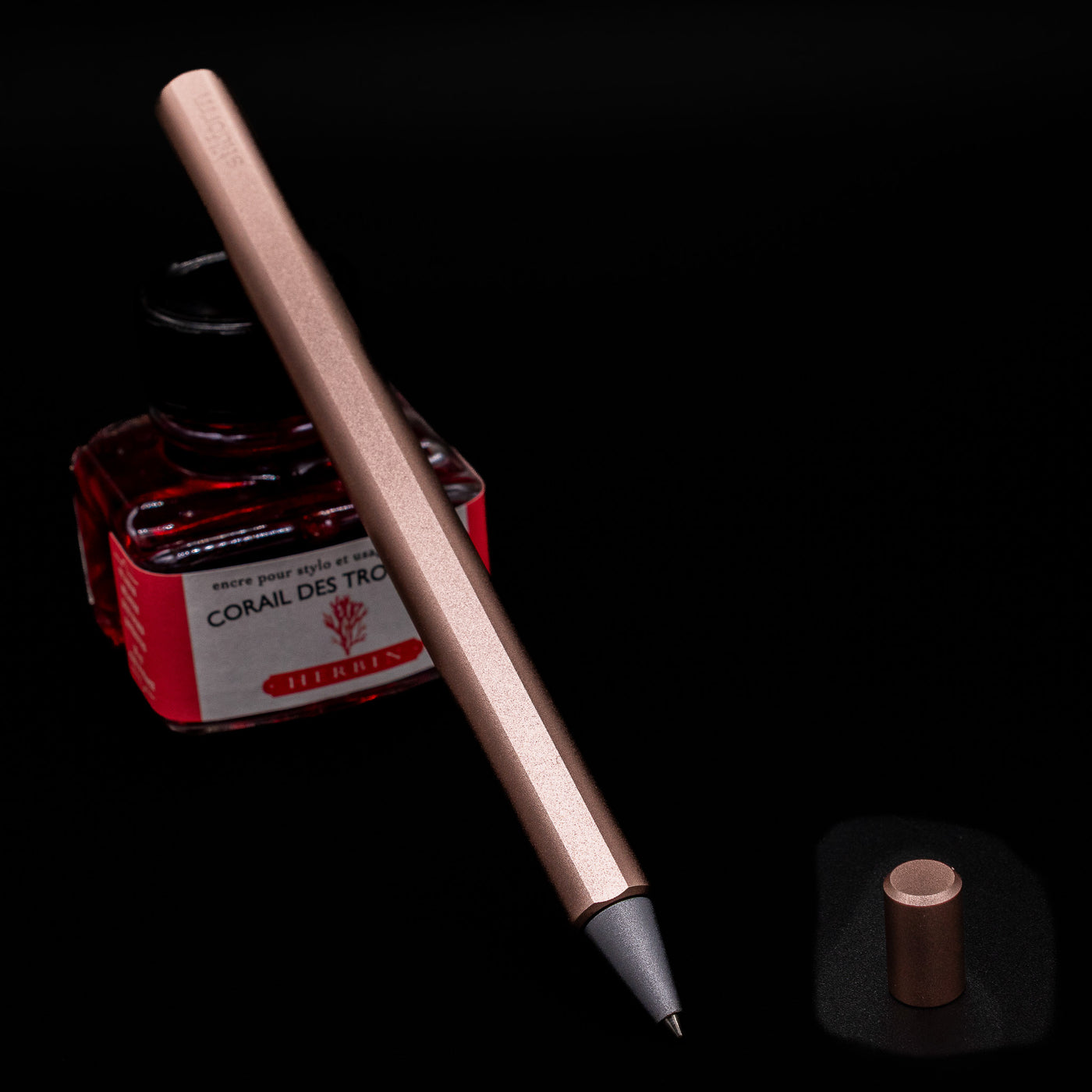 Stilform FLOW Rollerball Pen – Rose Moon Aluminium leaning on an ink bottle.