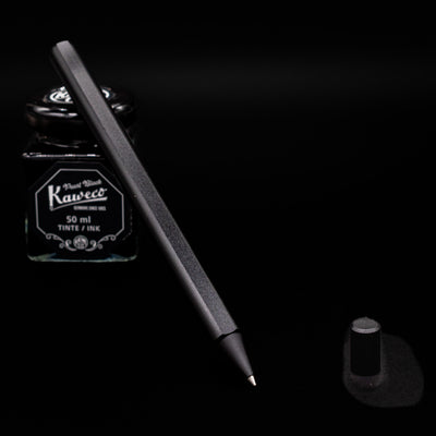 Stilform FLOW Rollerball Pen – Warp Black Aluminum uncapped leaning on an ink bottle.