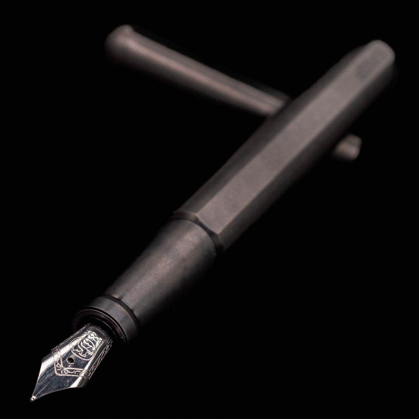Stilform INK Fountain Pen – Titanium DLC laying across its own cap, crossed, with a focus on the nib.