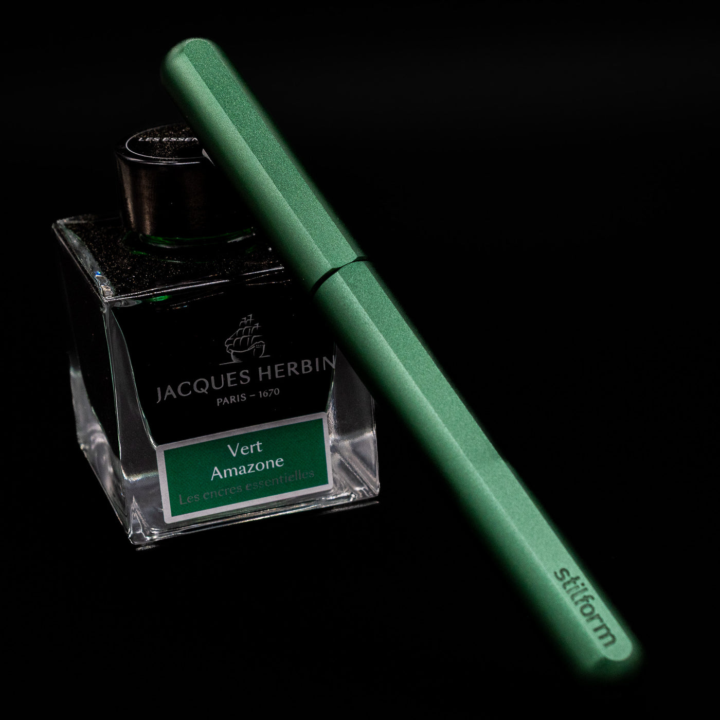 Stilform INK Fountain Pen – Aurora Green Aluminum capped, leaning against an ink bottle. 