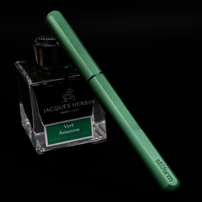 Stilform INK Fountain Pen – Aurora Green Aluminum capped, leaning against an ink bottle. 