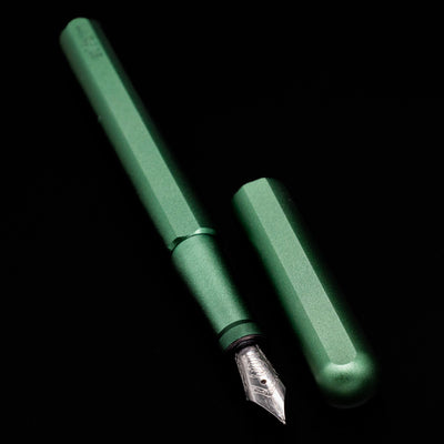  A full view of the Stilform INK Fountain Pen – Aurora Green Aluminum uncapped, with its cap laying next to the pen. 