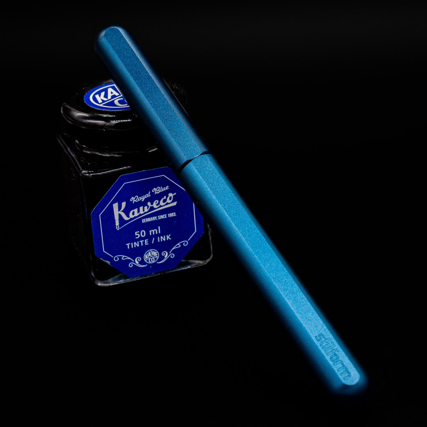 Stilform INK Fountain Pen – Night Sky Aluminum capped, leaning against an ink bottle. 