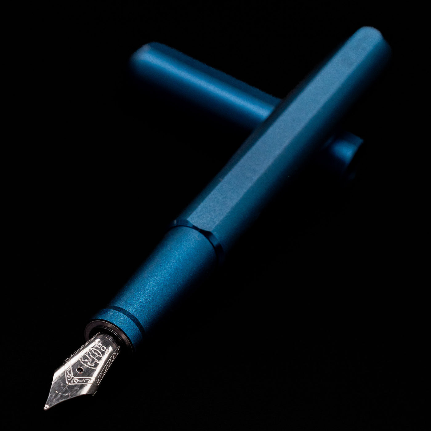 Stilform INK Fountain Pen – Night Sky Aluminum laying across its own cap, crossed, with a focus on the nib.