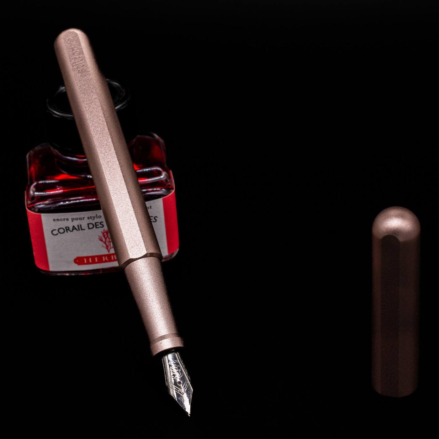 Stilform INK Fountain Pen – Rose Moon Aluminum leaning on an ink bottle uncapped showcasing the detailing on the nib.