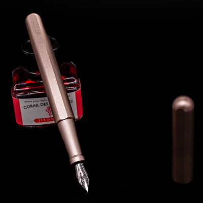 Stilform INK Fountain Pen – Rose Moon Aluminum leaning on an ink bottle uncapped showcasing the detailing on the nib.