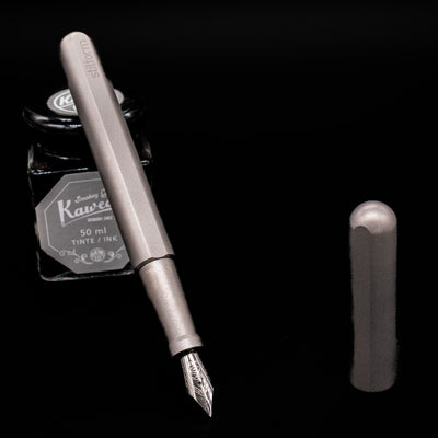 Stilform INK Fountain Pen – Titanium Matte leaning on an ink bottle uncapped showcasing the detailing on the nib.