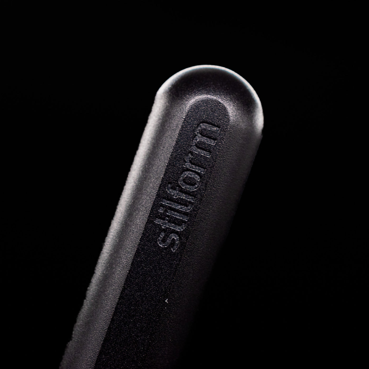 A macro shot of the logo on the bottom of the body of the Stilform INK Fountain Pen – Warp Black Aluminum.