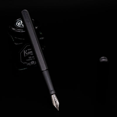 Stilform INK Fountain Pen – Warp Black Aluminum leaning on an ink bottle uncapped showcasing the detailing on the nib.