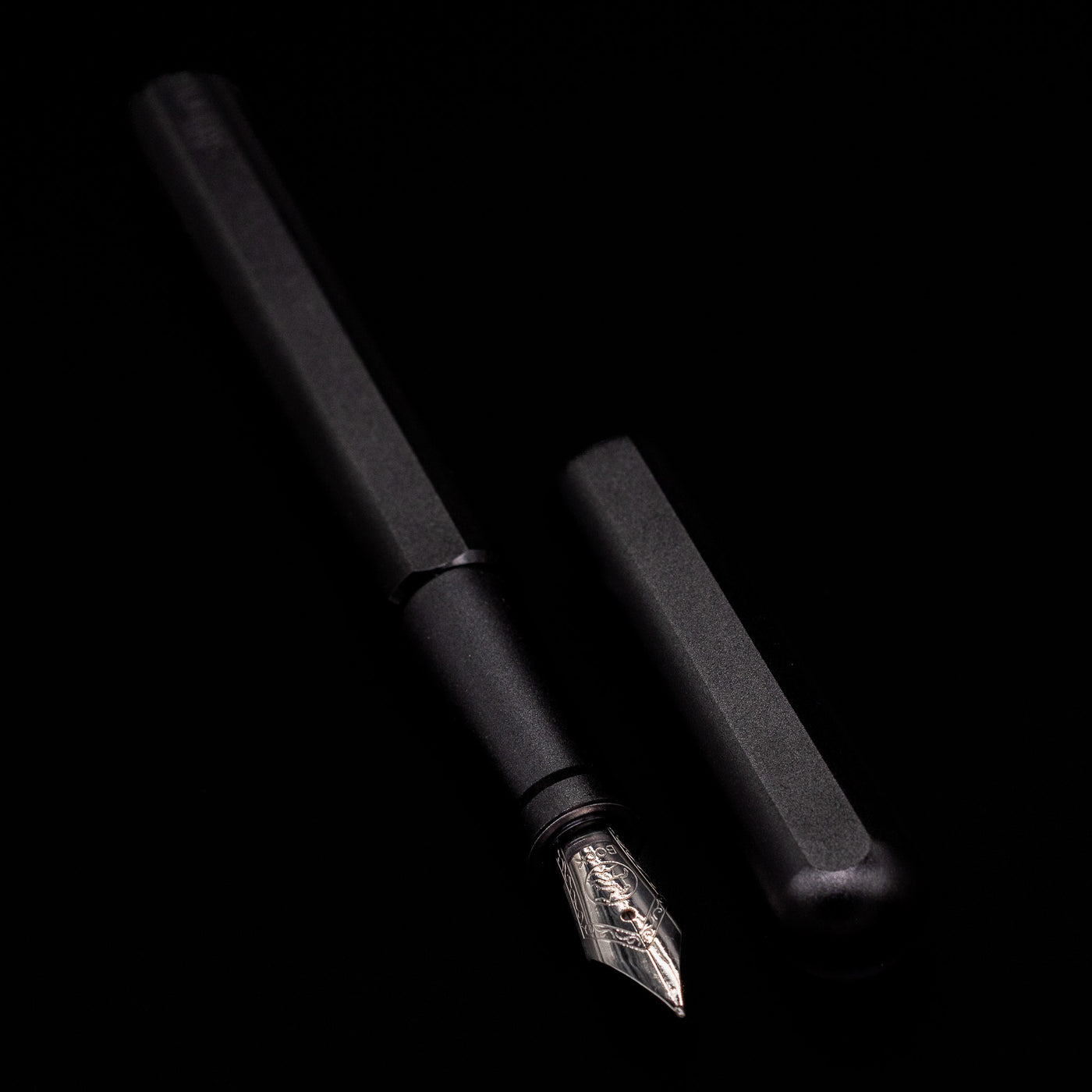  A full view of the Stilform INK Fountain Pen – Warp Black Aluminum uncapped, with its cap laying next to the pen. 