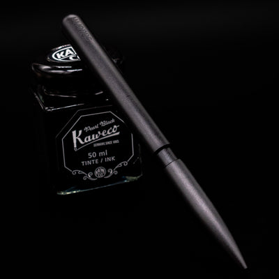 Stilform PEN Ballpoint Pen – Warp Black Aluminum leaning on an ink bottle.