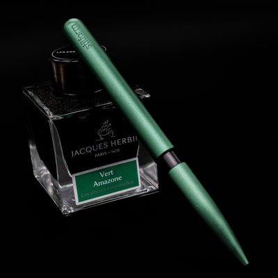 Stilform PEN Ballpoint Pen – Aurora Green Aluminum leaning on an ink bottle.
