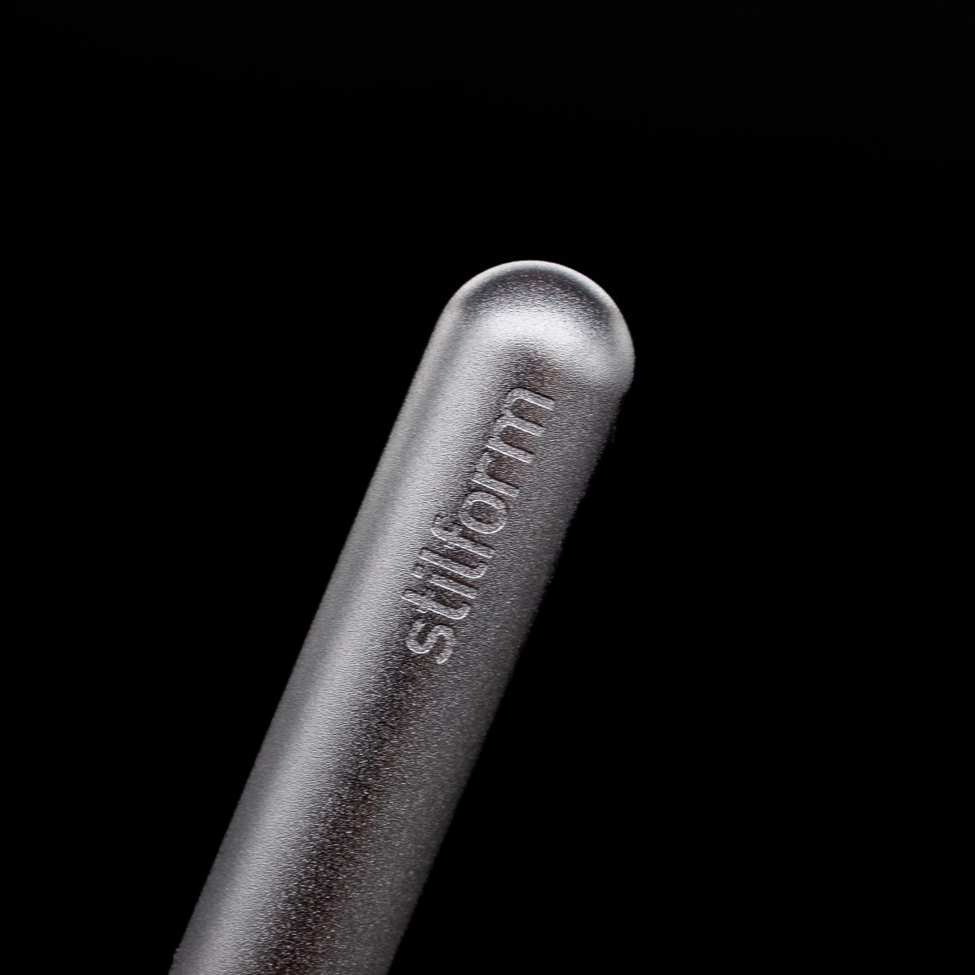 A macro shot of the logo on the cap of the Stilform PEN Ballpoint Pen – Comet Grey Aluminum.