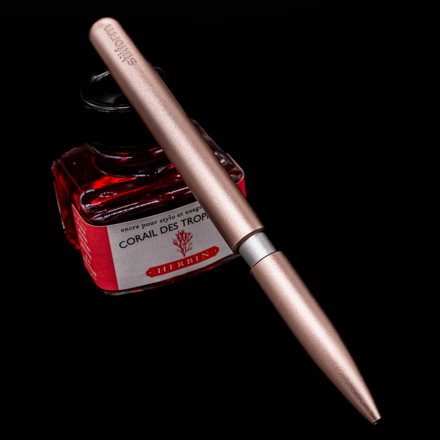 Stilform PEN Ballpoint Pen – Rose Moon Aluminum leaning on an ink bottle.