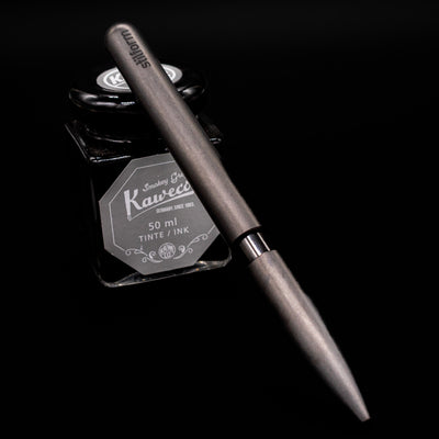 Stilform PEN Ballpoint Pen – Titanium DLC leaning on an ink bottle.