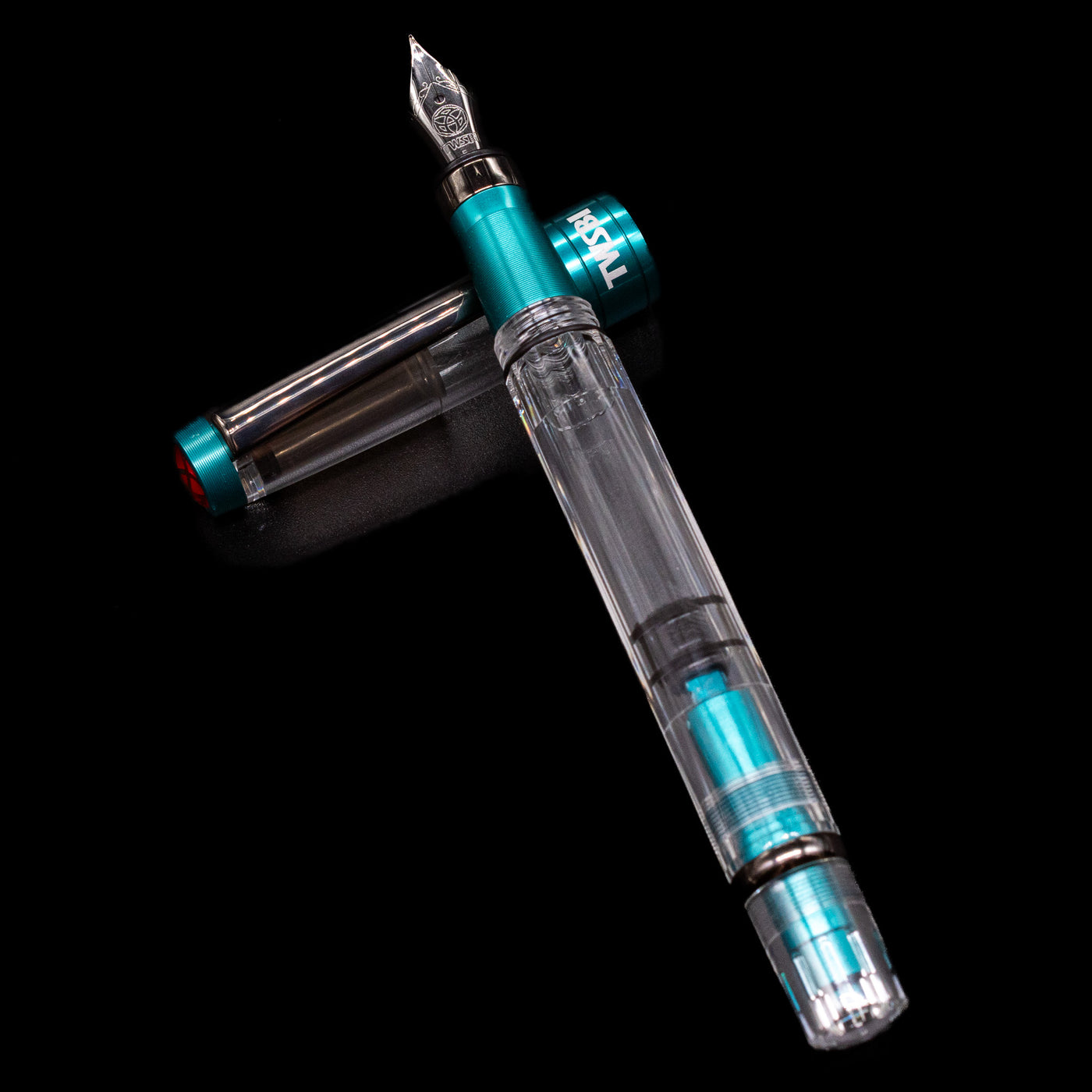TWSBI Diamond 580 Caribbean Blue & Onyx Fountain Pen - Preowned laying on top of its cap in a crossed position showing full view of the entire uncapped pen.