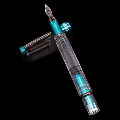 TWSBI Diamond 580 Caribbean Blue & Onyx Fountain Pen - Preowned laying on top of its cap in a crossed position showing full view of the entire uncapped pen.