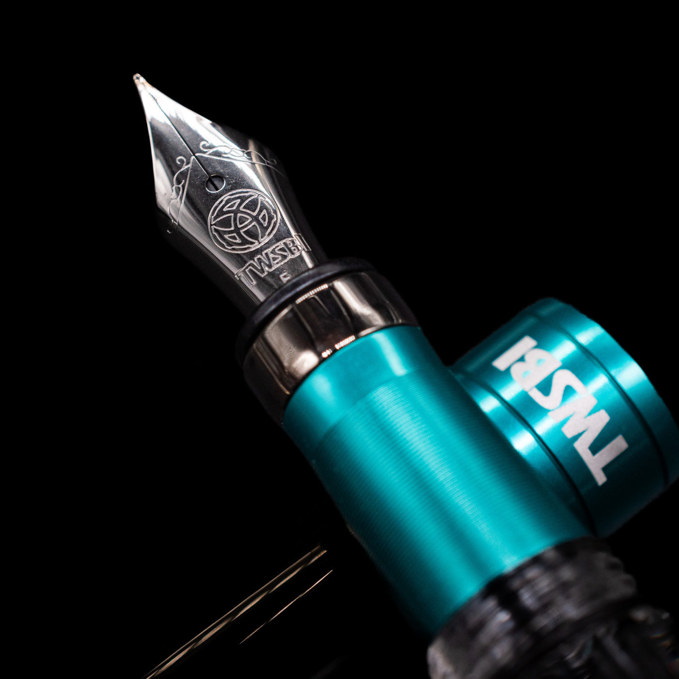  A macro shot of the nib with its intricate detailing and logo engraving for the TWSBI Diamond 580 Caribbean Blue & Onyx Fountain Pen - Preowned.