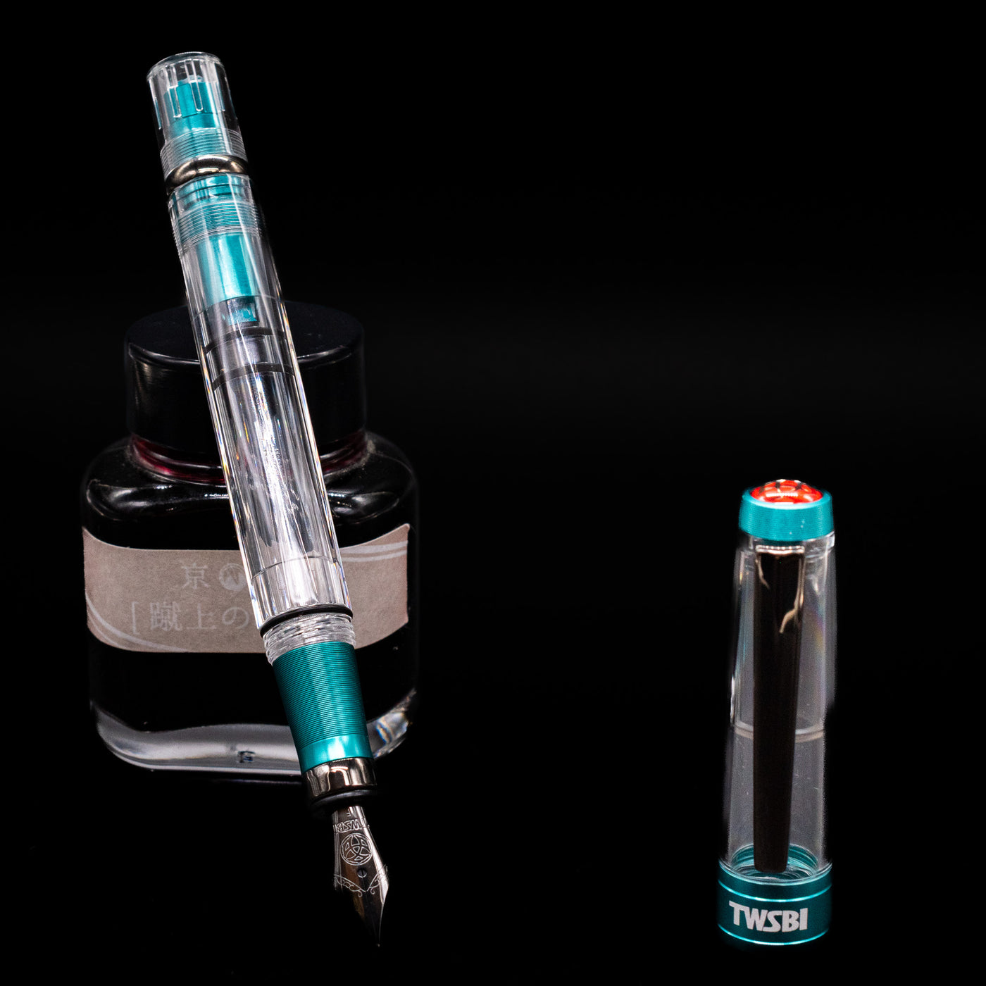 TWSBI Diamond 580 Caribbean Blue & Onyx Fountain Pen - Preowned leaning on an ink bottle uncapped showcasing the detailing on the nib.