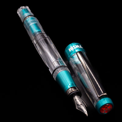 A full view of the TWSBI Diamond 580 Caribbean Blue & Onyx Fountain Pen - Preowned uncapped, with its cap laying next to the pen. 