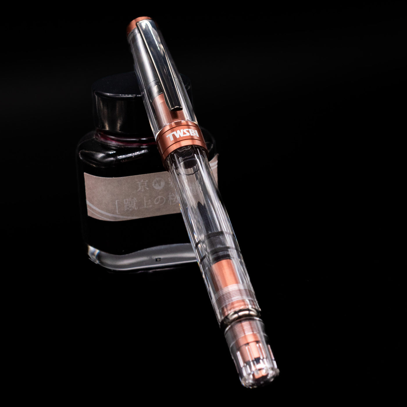 TWSBI Diamond 580ALR Affogato & Onyx Fountain Pen - Preowned capped, leaning against an ink bottle. 